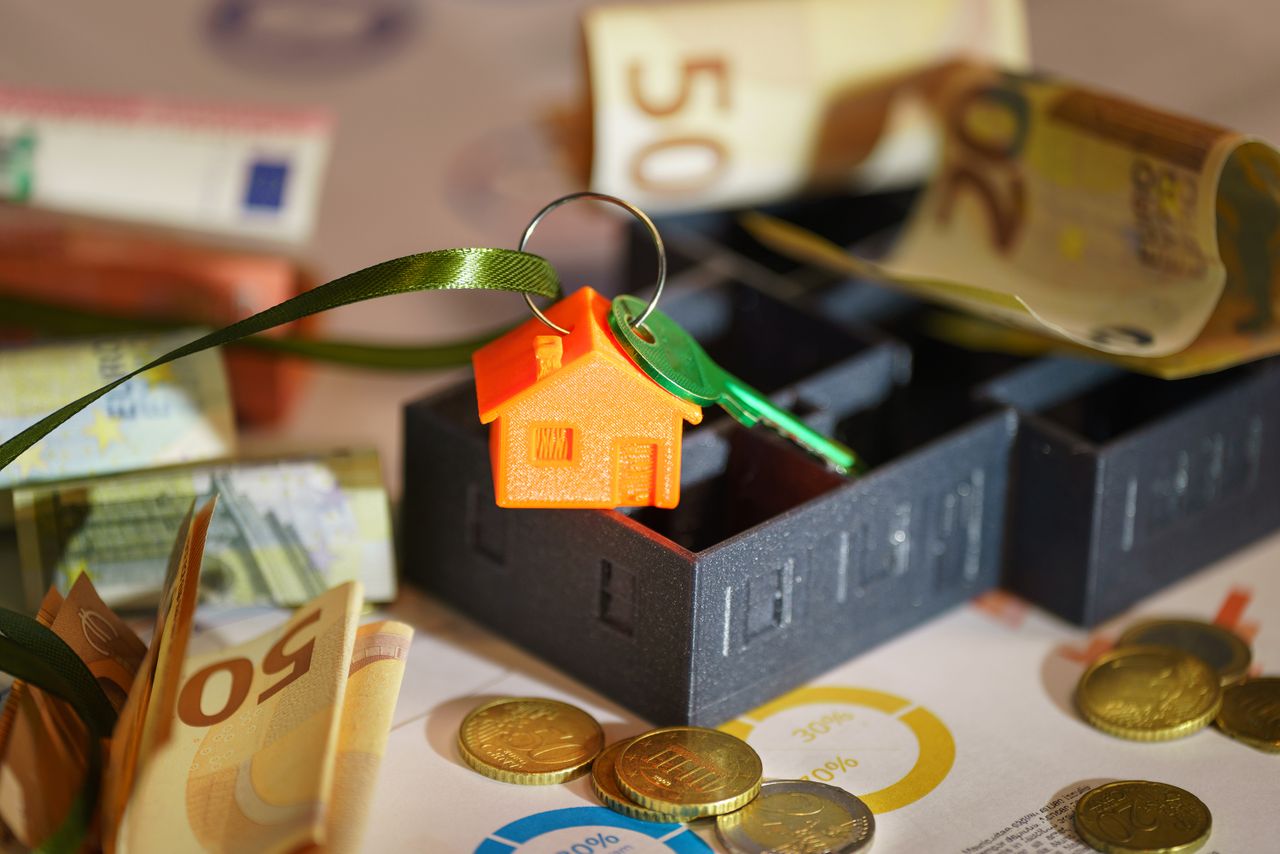 Home Image depicting real estate investment with keychain, euros, and financial charts.